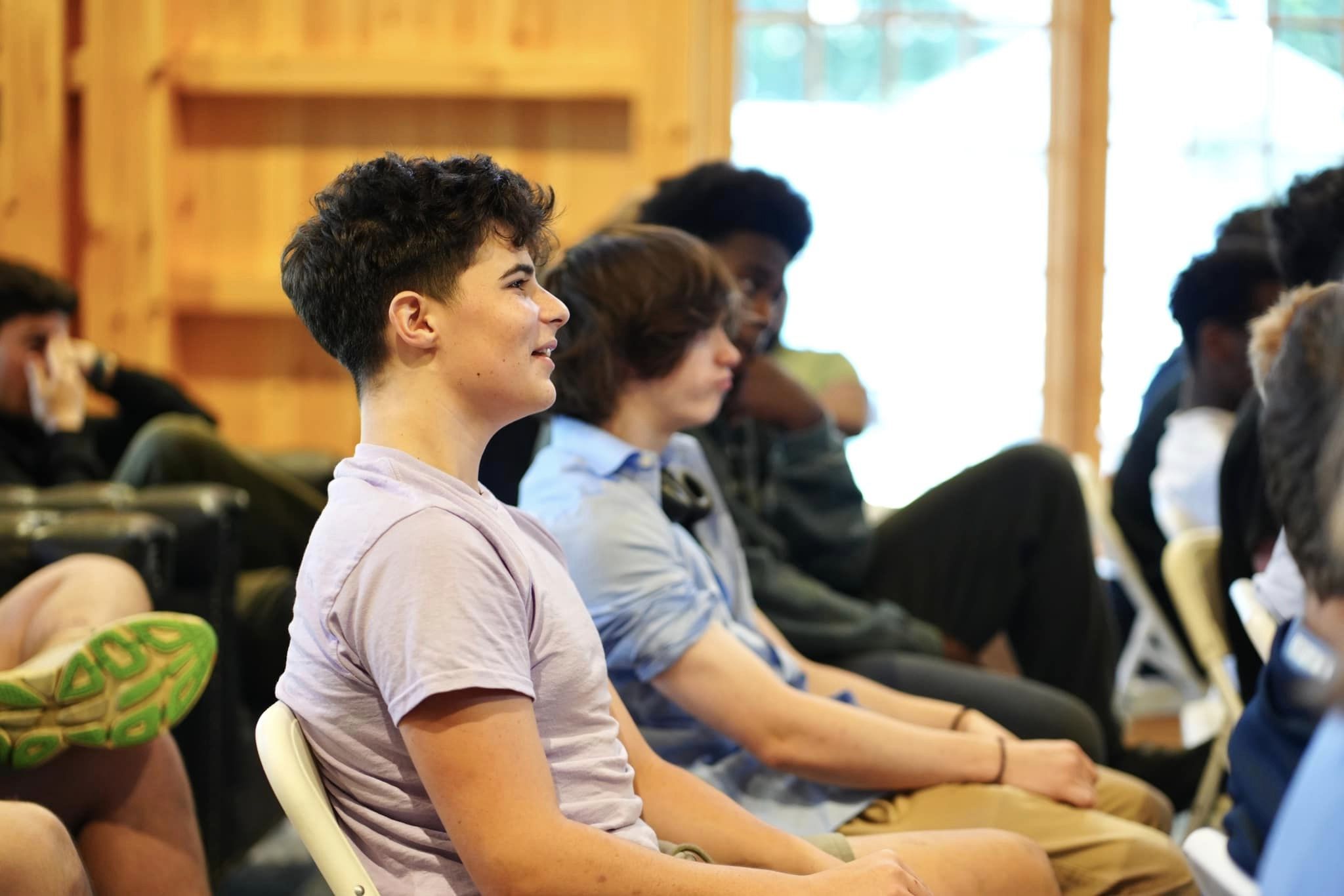 A group of people seated indoors, attentively listening to something off-camera.